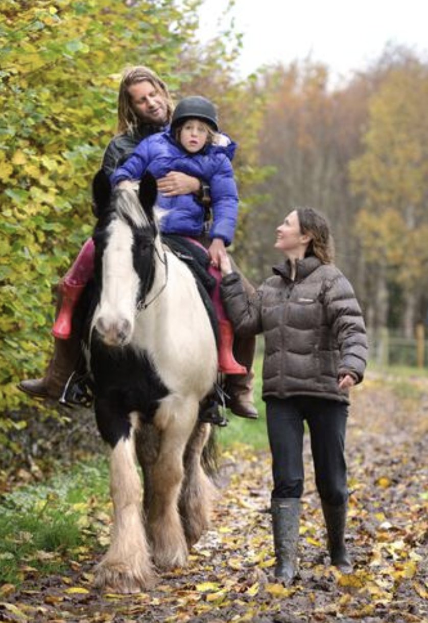 A child riding a horse with helpers